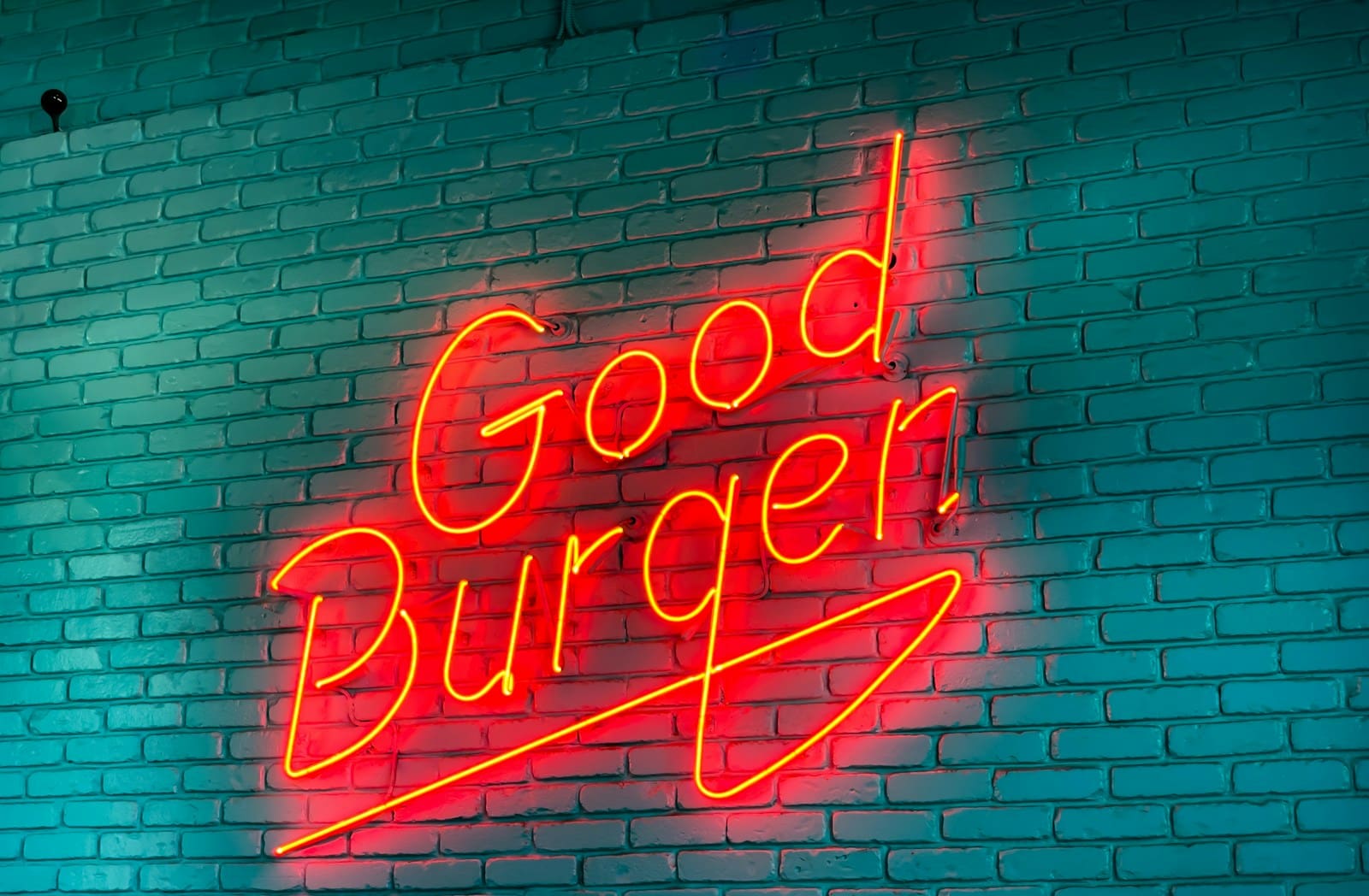 a neon sign on a brick wall that says Good Burger